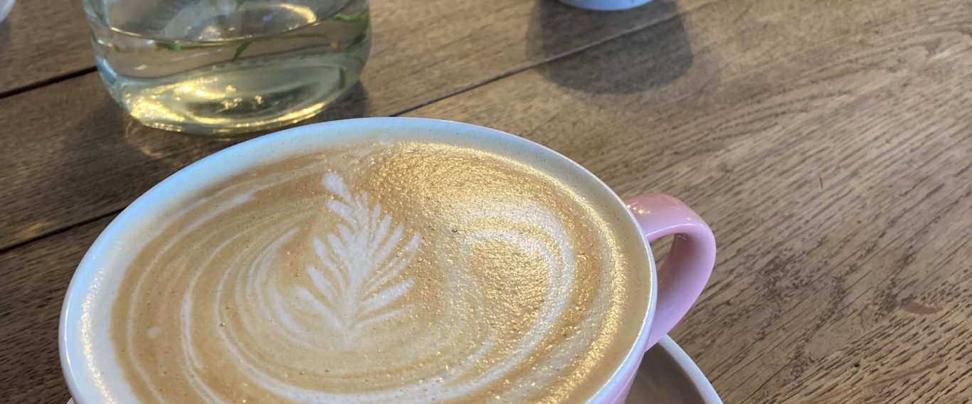 Ein herzliches Kennenlernen bei einer Tasse Kaffee Rosane Tasse mit Milchkaffee auf einem rustikalen Tisch